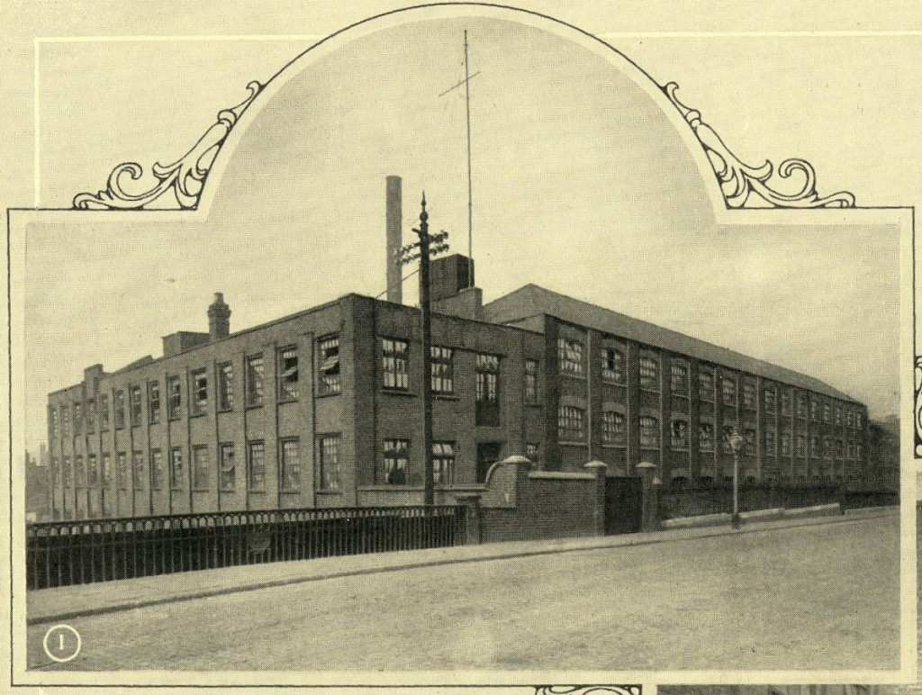 Large factory on several floors, next to canal bridge with decorative iron railings