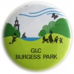 Circular badge with graphic showing lake, trees and church, with kids and pram, and text 'GLC Burgess Park'.