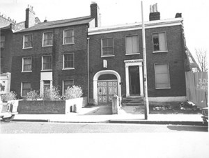 B/W image of two former victorian house frontages with arched double dooorway in one