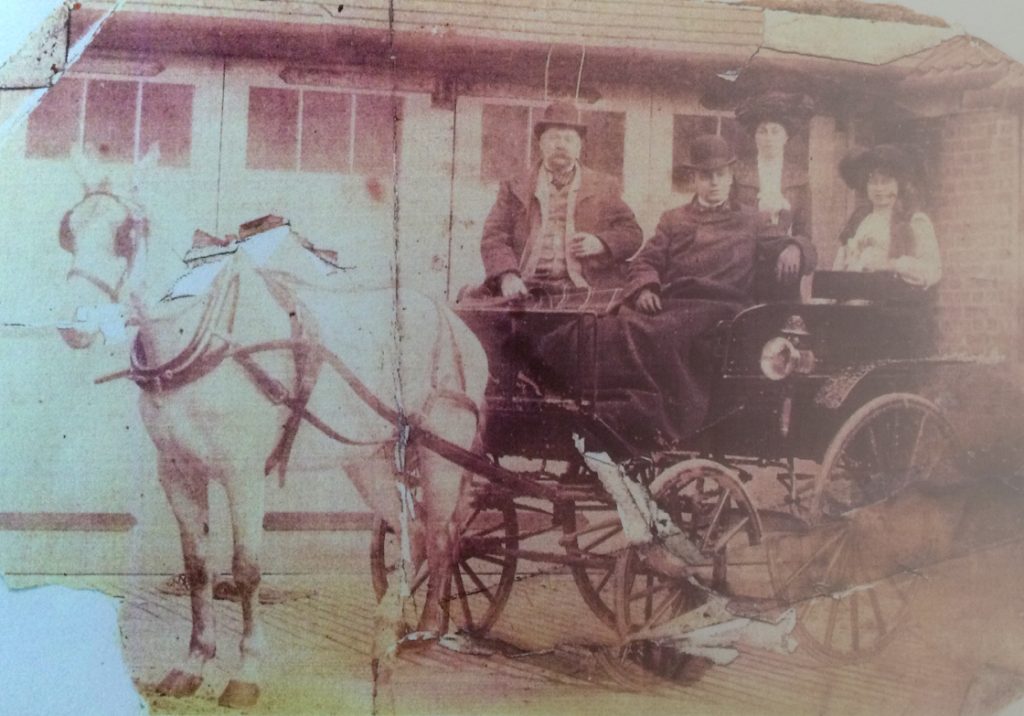 2 Edwardian gents and 2 ladies seated ona 4-wheel carriage with single white horse 